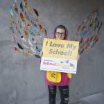 student holding school choice week sign wall mural
