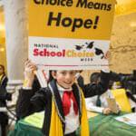 Girl holding a school choice poster wearing a scarf