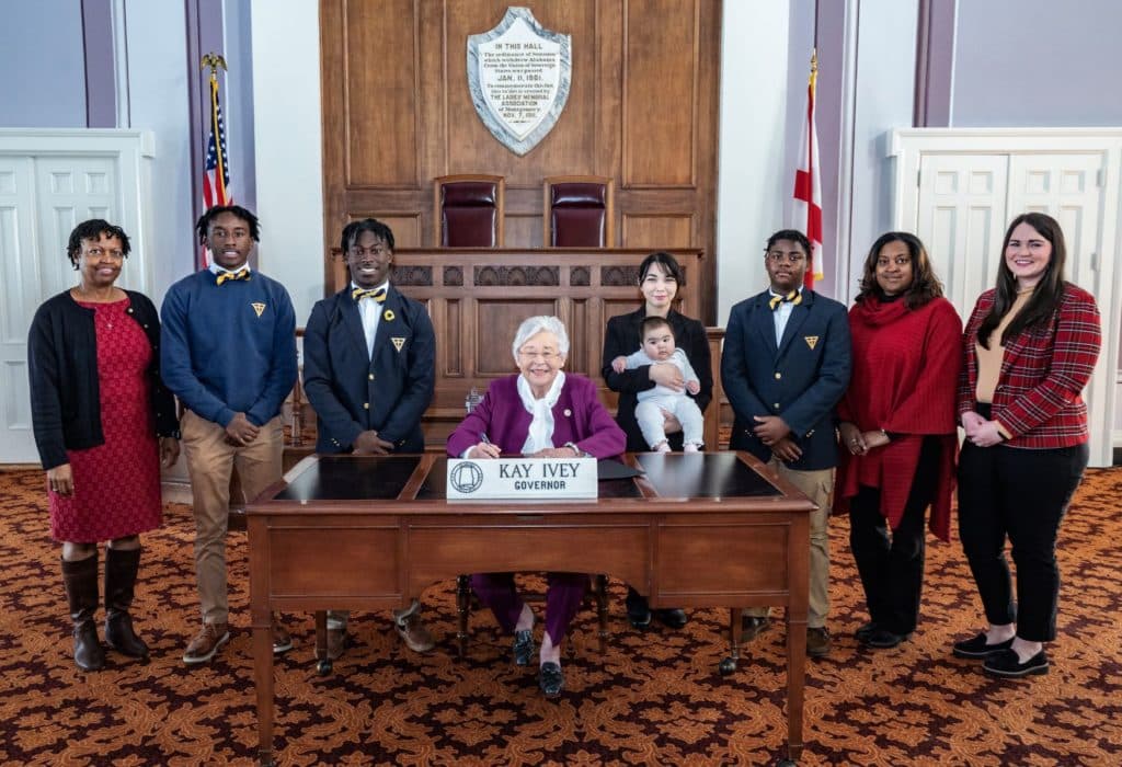 Governor Kay Ivey signs the Alabama School Choice Week proclamation with representatives from the Alabama Opportunity scholarship fund and scholarship recipient students.