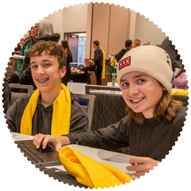 Two students working on a laptop smile for the camera