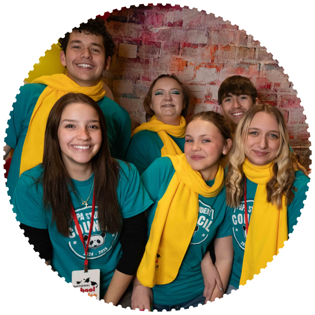 A group of students wearing scarves smile for the camera
