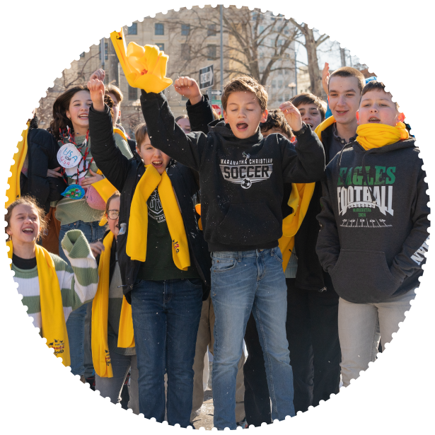 A group of students at a capitol rally cheer and jump