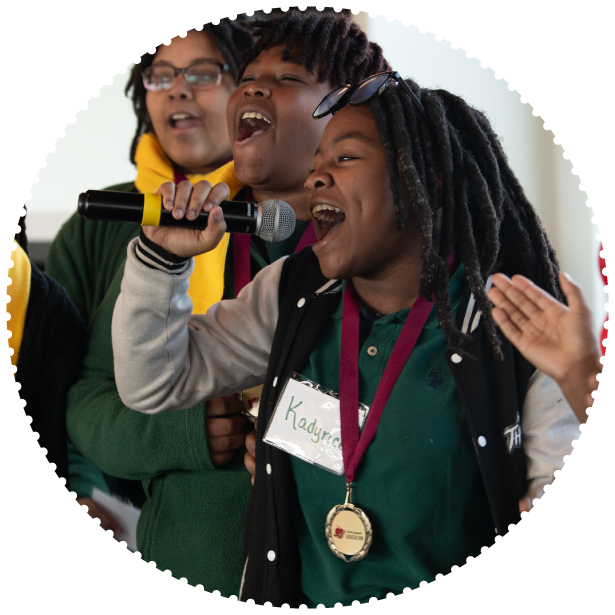 A student holding a microphone sings for the crowd