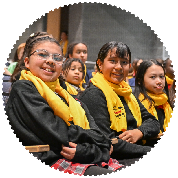 A group of students wearing scarves smile for a photo in an auditorium